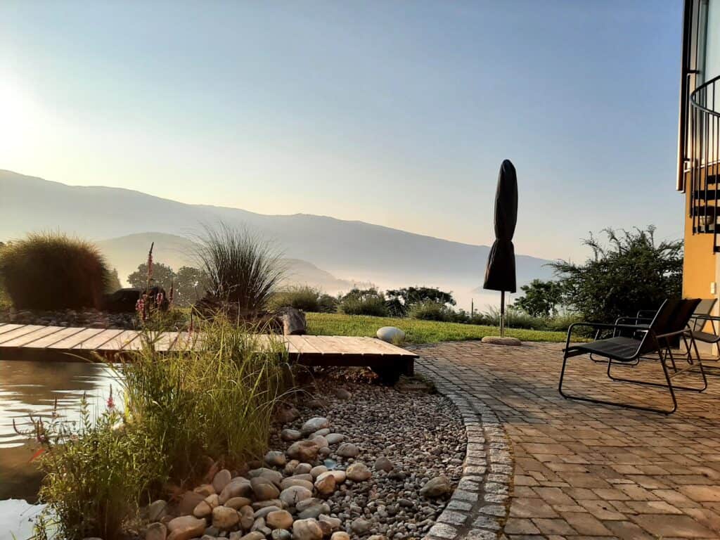 Ruhiges Weingut vulgo Ritter mit Blick auf die Berge, Gartenterrasse mit Liegestühlen, gepflegtes Weingut, idyllische Atmosphäre, Weinverkostung, entspannte Auszeit in der Natur, Weinberg, malerische Kulisse, Weinreise, Weinliebhaber, Dearurne, Weingarten.