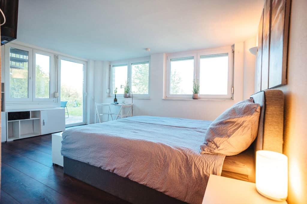 Schlafzimmer im Weingut Vulgo Ritter mit moderner Einrichtung und großen Fenstern, umgeben von Weinbergen, perfekte Unterkunft für Weinliebhaber und Weinreisen.